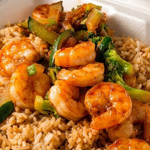 Shrimp and vegetable stir-fry with brown rice in a white takeout container.